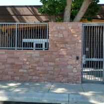 Iron "Tree Bark" style fencing and security gate mounted around rock. Loveland, CO